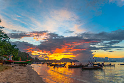 Sailboats moored on sea against sky during sunset