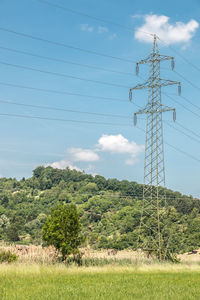 Low angle view of electricity pylon on field against sky