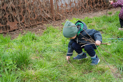 The child collects dry branches from the grass. the concept of caring for the environment.