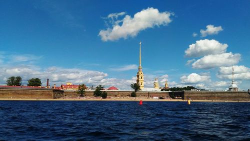 View of city at waterfront against cloudy sky