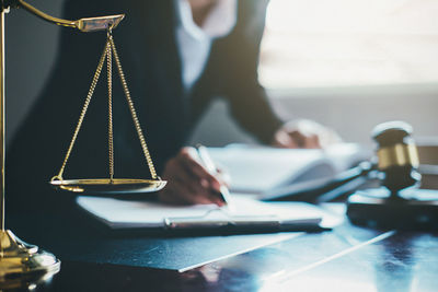 Midsection of lawyer writing while sitting in office