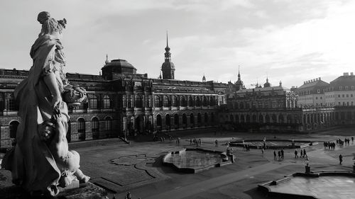 Statue in city against cloudy sky