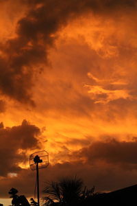 Low angle view of silhouette street light against dramatic sky