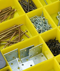 Various metal screws in separate yellow plastic containers. the concept of order and organization of