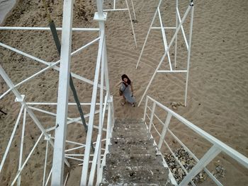 High angle view of woman standing by lookout tower steps at sandy beach