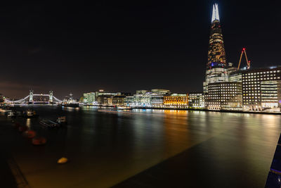 Illuminated buildings in city by thames river at night