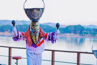 Man wearing traditional clothing dancing against river during sunset