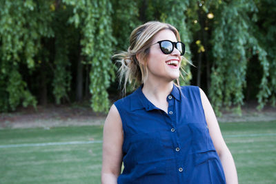 Beautiful young woman wearing sunglasses against trees