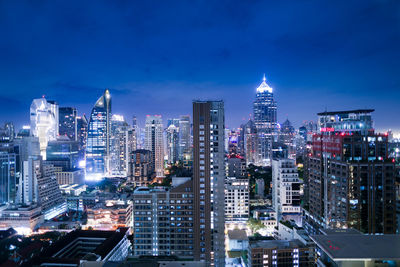 Illuminated buildings in city against blue sky