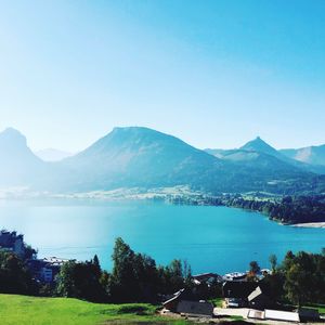 Scenic view of lake and mountains against clear blue sky