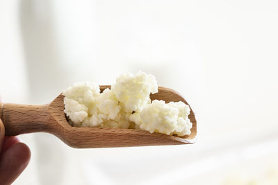 Close-up of hand holding ice cream over white background