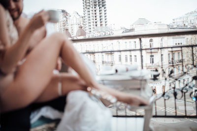 Midsection of man sitting against buildings in city