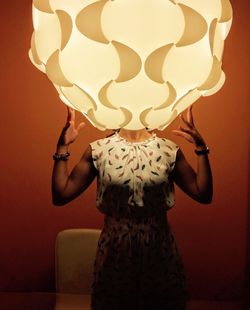 Woman standing with head inside illuminated lighting equipment