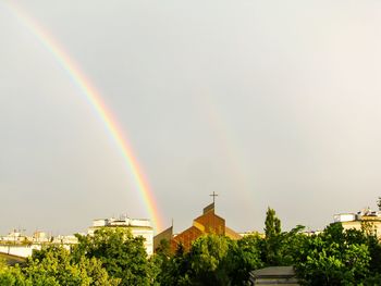 Rainbow over buildings in city against sky