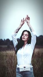 Happy woman standing on field against sky