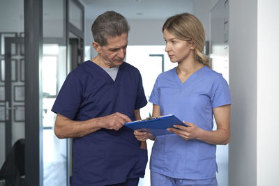 Doctor reading reports by female nurse at hospital