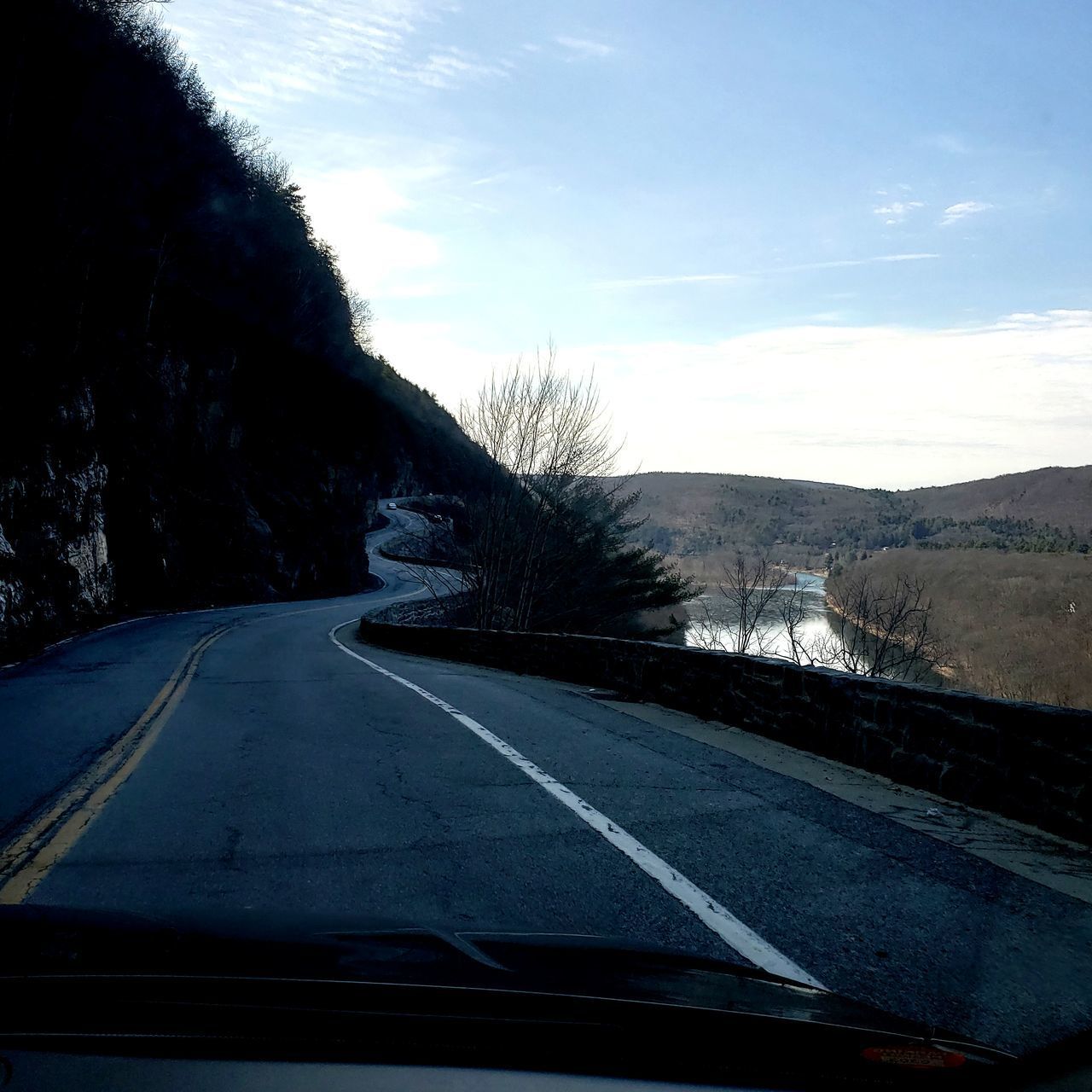 ROAD SEEN THROUGH CAR WINDSHIELD AGAINST SKY