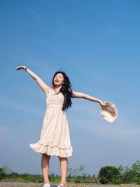 Full length of woman standing against blue sky