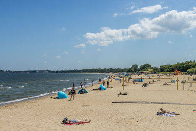 Panoramic view of people on beach against sky