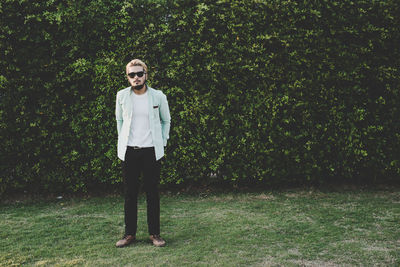 Full length of man standing on field against plants at park