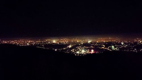 Illuminated cityscape against sky at night