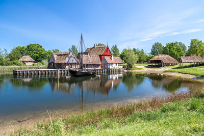 Houses by lake against blue sky