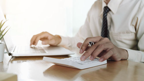 Midsection of woman using smart phone on table