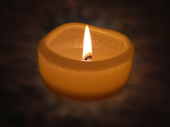 Close-up of lit tea light candle in darkroom
