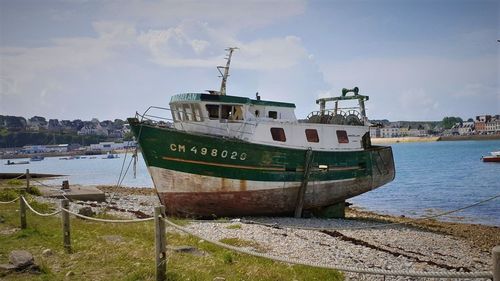 Boat moored on beach against sky