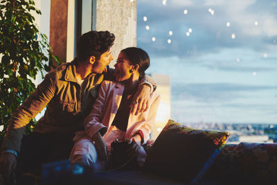 Mixed race couple sitting in illuminated garden at sunset