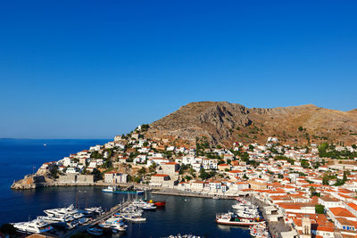 Aerial view of city by sea against clear blue sky