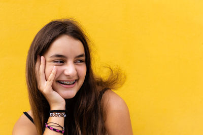 Portrait of young woman against yellow background