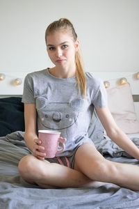 Portrait of young woman drinking coffee at home