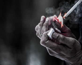Close-up of hand igniting cigarette with matchstick