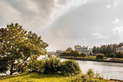 Scenic view of river by buildings against sky