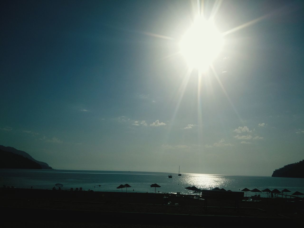 sea, water, horizon over water, sun, scenics, tranquil scene, tranquility, sunbeam, beauty in nature, sky, sunlight, silhouette, beach, nature, idyllic, reflection, lens flare, shore, blue, outdoors