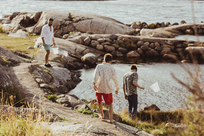 Rear view of boy with sibling while father standing over rock during weekend