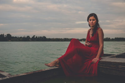 Portrait of woman standing by sea against sky