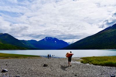 Rear view of men by lake against sky