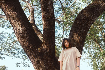 Low angle view of woman standing by tree