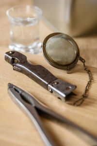 High angle view of pliers and tea strainer on wooden table