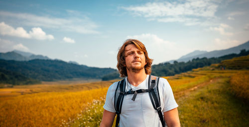 Mid adult man standing on field against sky