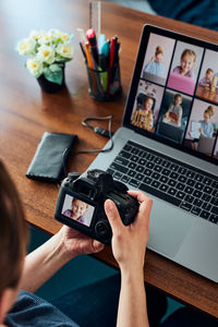 High angle view of woman holding camera sitting by table
