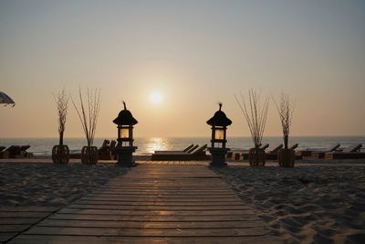 Silhouette pier on beach against sky during sunset