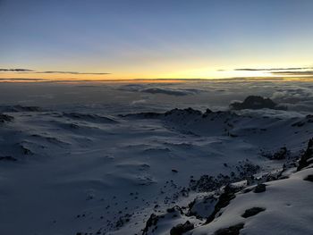 Scenic view of snow covered mountains against sky at sunset