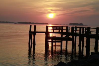 Silhouette pier over lake at sunset