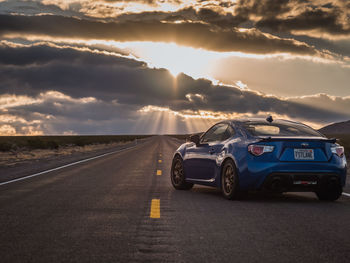 Cars on road against sky during sunset