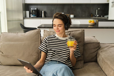 Portrait of woman using laptop while sitting on sofa at home