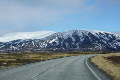 Road by snowcapped mountains against sky