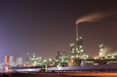 Low angle view of illuminated industry against sky at night